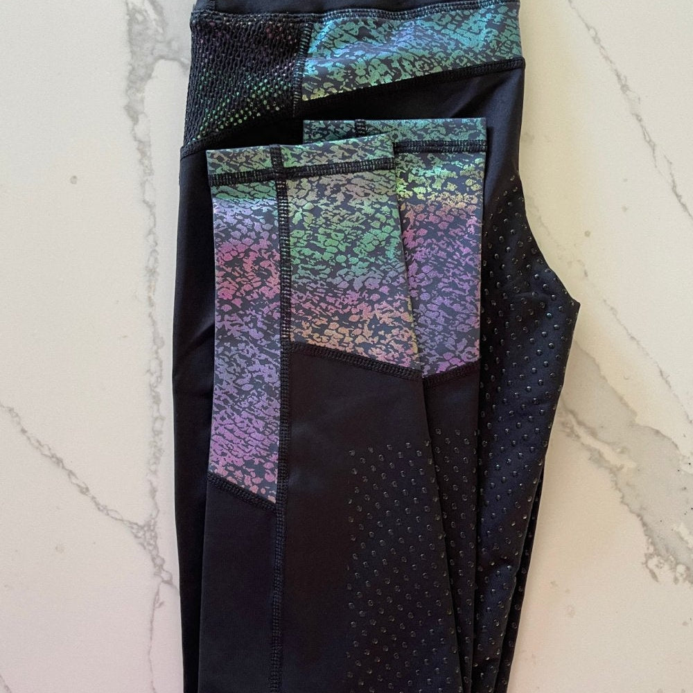 Multicolored horse riding tights with patterned thigh panels on marble background.