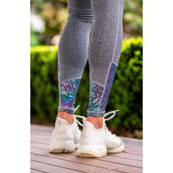 Person wearing patterned horse riding tights and white sneakers.