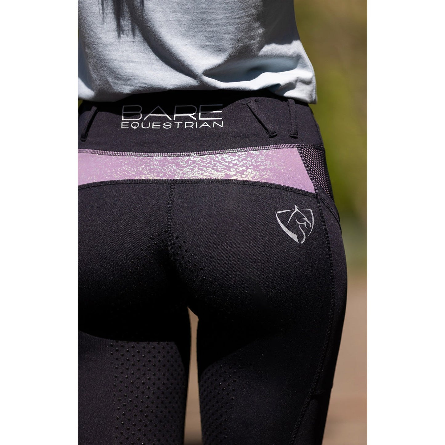 Close-up of black and purple horse riding tights by BARE Equestrian.