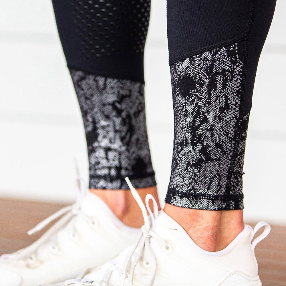 Close-up of patterned black horse riding tights with white sneakers.