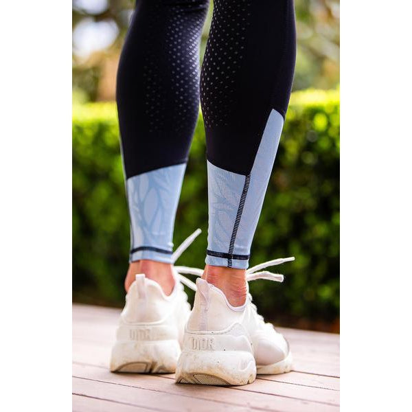 Person wearing blue and black horse riding tights with white sneakers.