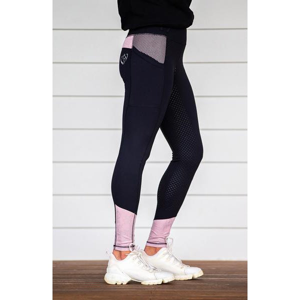 Person standing sideways wearing black and pink horse riding tights.