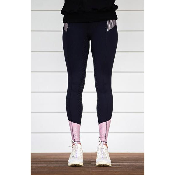 Person wearing black and pink horse riding tights with white shoes.
