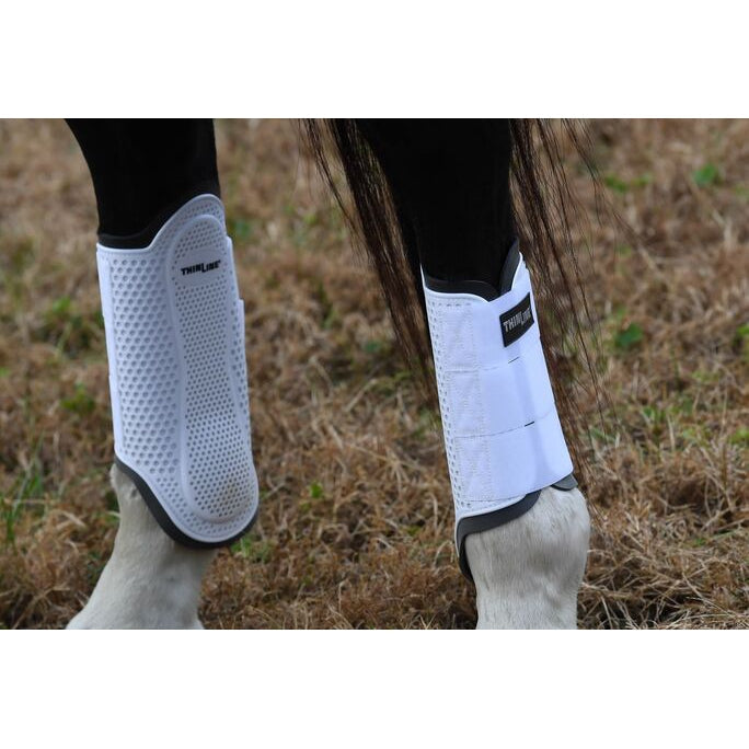 Horse legs wearing Thinline Global white protective leg boots.