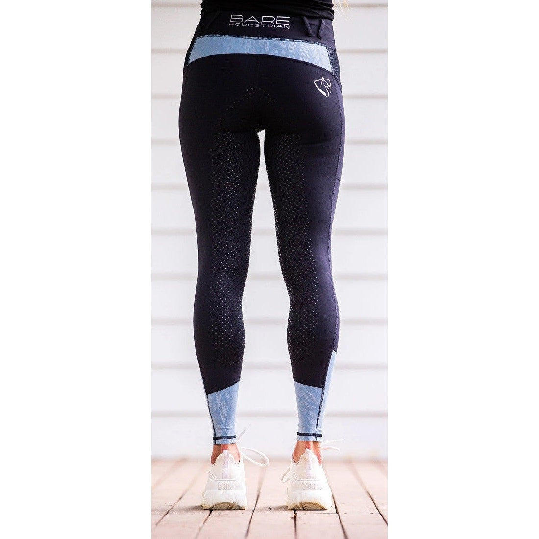 Person standing in horse riding tights with silicone grip pattern.
