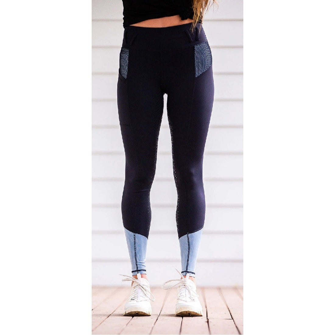 Person standing in black horse riding tights with mesh details.