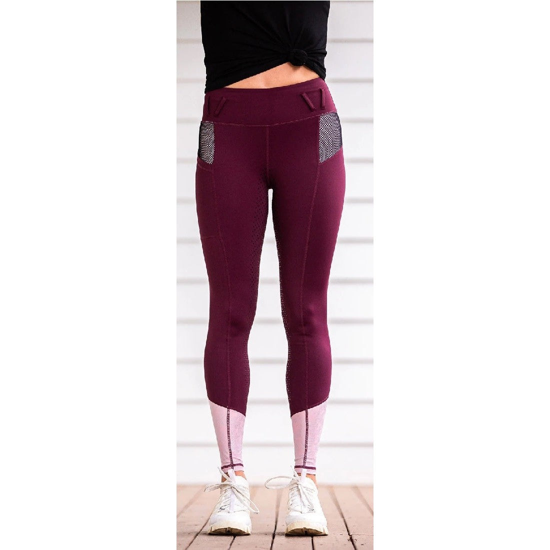 Person wearing maroon horse riding tights with mesh pockets.