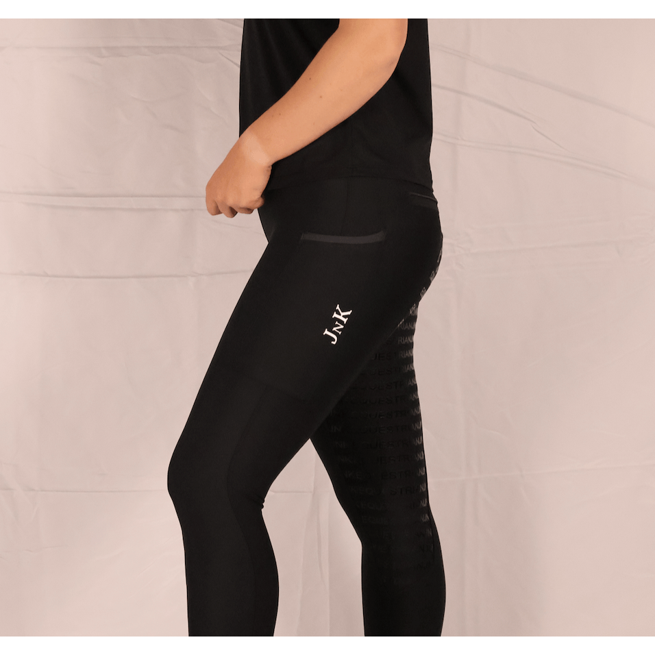 Person modeling black horse riding tights against a light background.