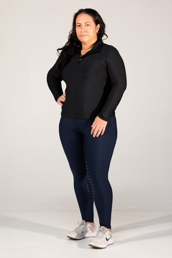 Woman wearing a black long-sleeve top and navy leggings on a white background