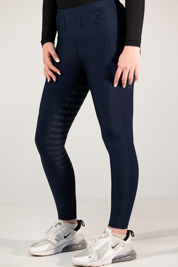 Person wearing navy leggings with text pattern and black long-sleeve top on a light gray background