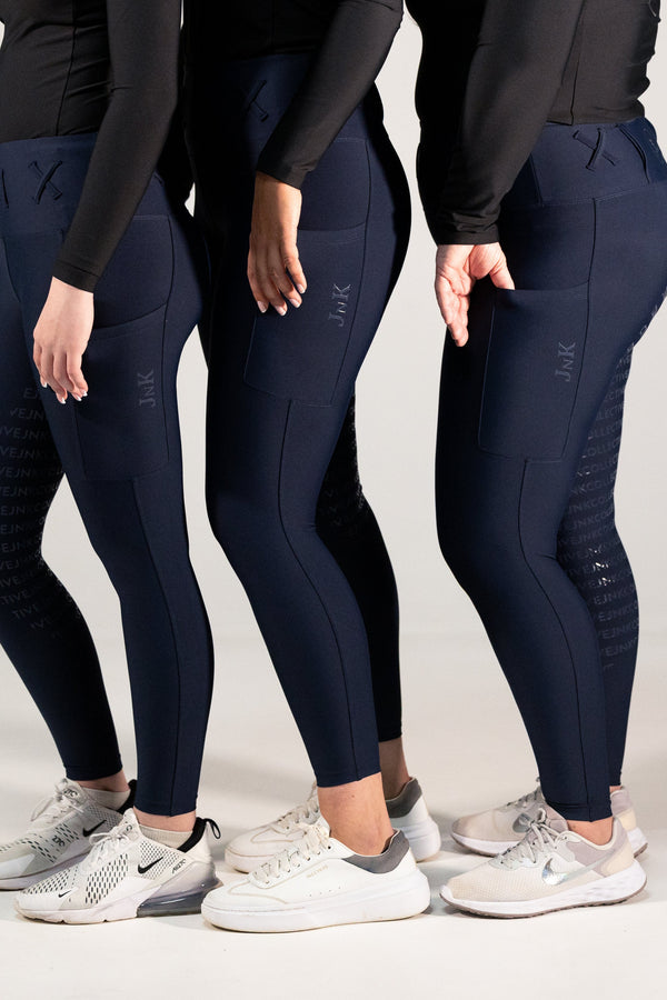 Three people wearing navy blue leggings with a subtle pattern on a light gray background