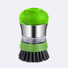 A green and stainless steel dishwashing brush with a transparent soap dispenser and black bristles, isolated on a white background.