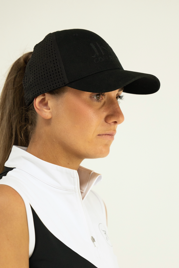 Woman wearing a black cap and white shirt against a plain background