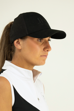 Woman wearing a black cap and white shirt against a plain background
