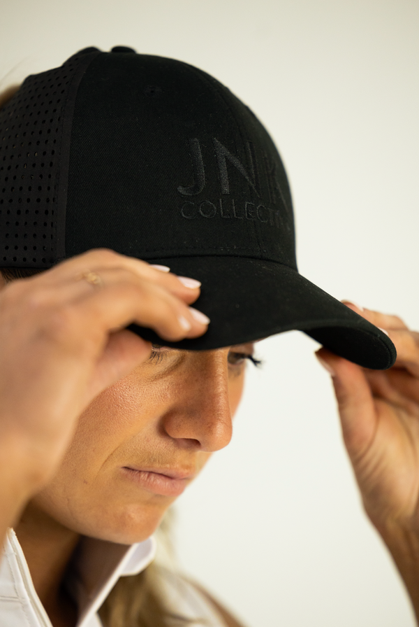 Person wearing a black cap with 'JN Collection' logo on a plain background