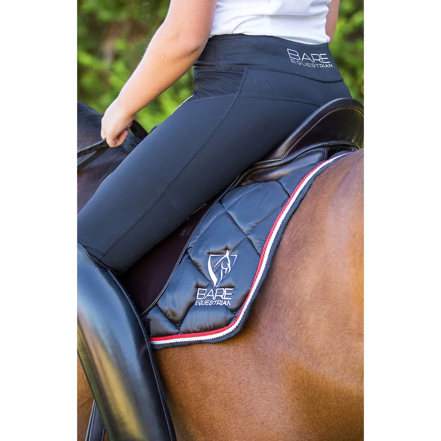 Rider wearing black horse riding tights on a brown horse.