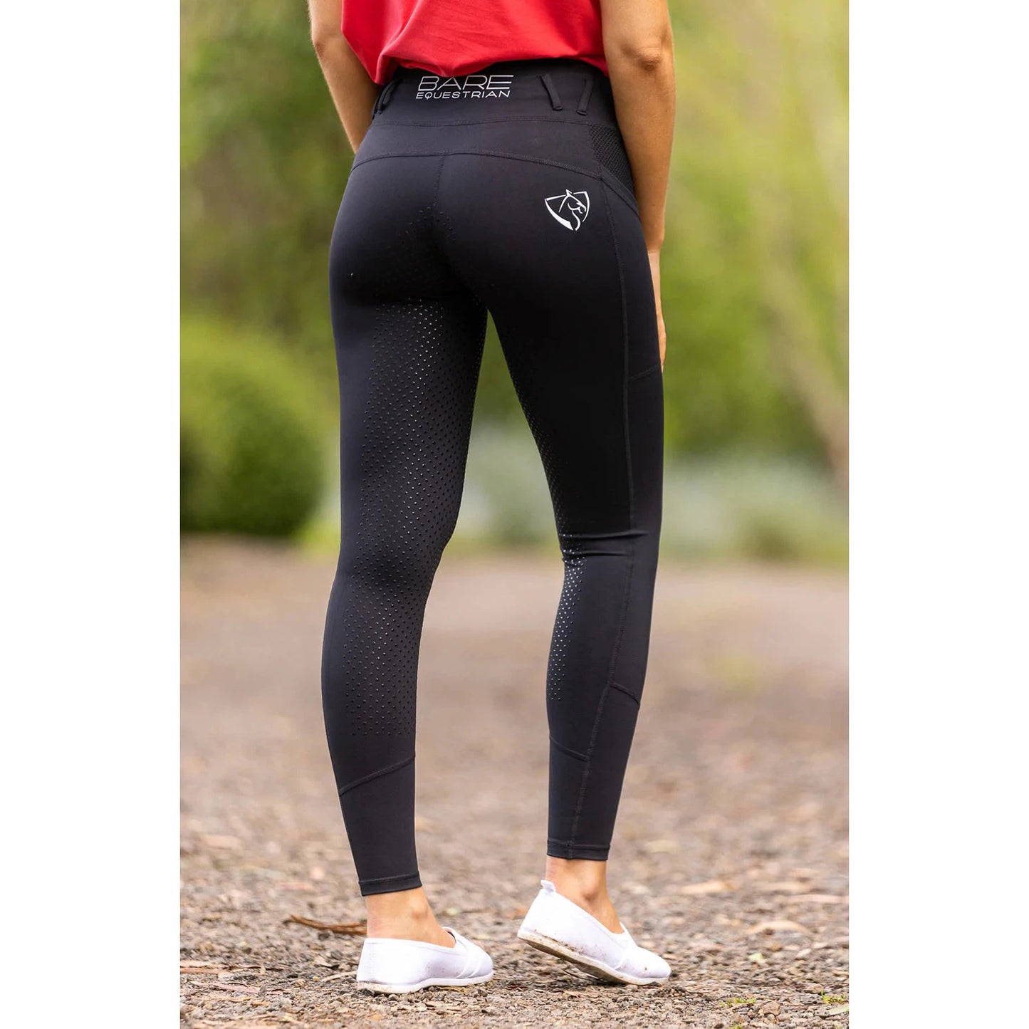 Person standing in black horse riding tights with dotted pattern.