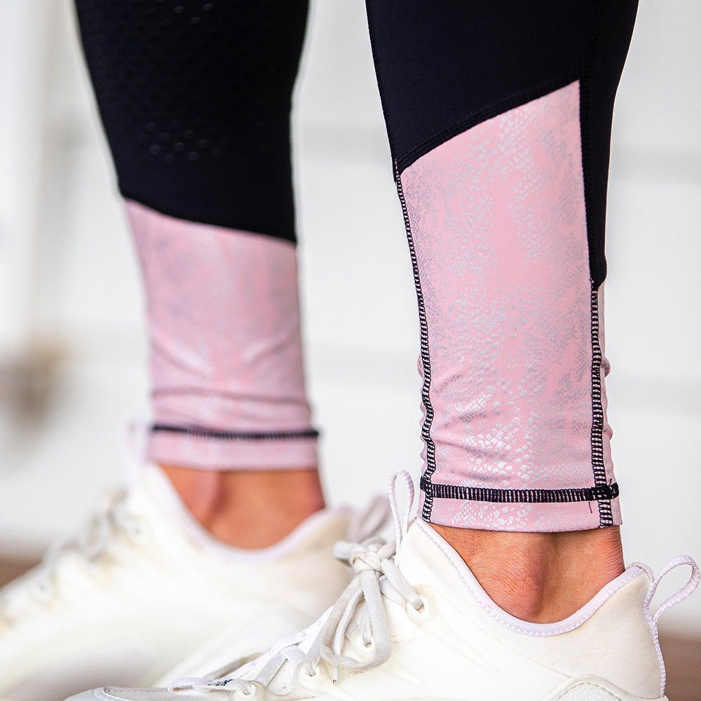 Close-up of black and pink horse riding tights with white shoes.