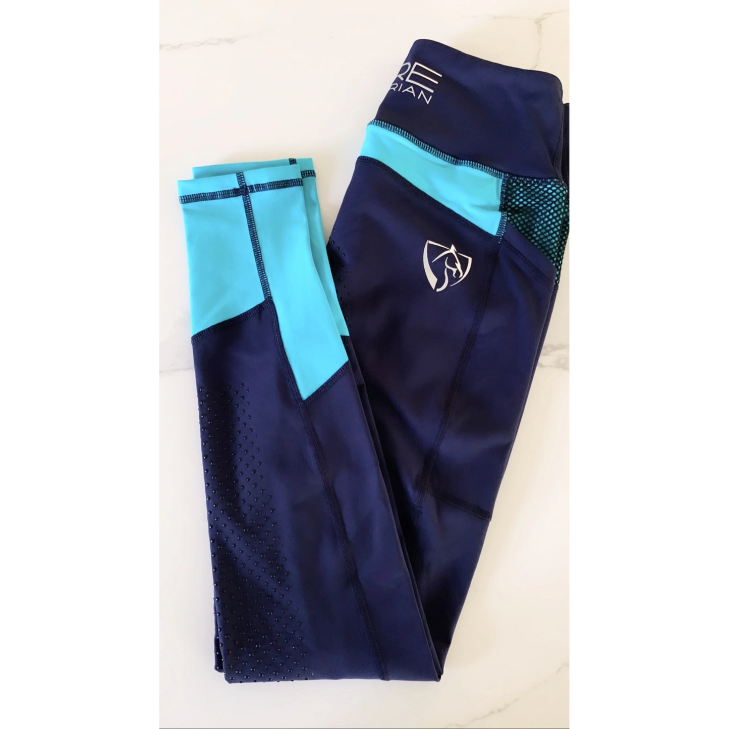 Navy and turquoise horse riding tights with patterned knee patches.