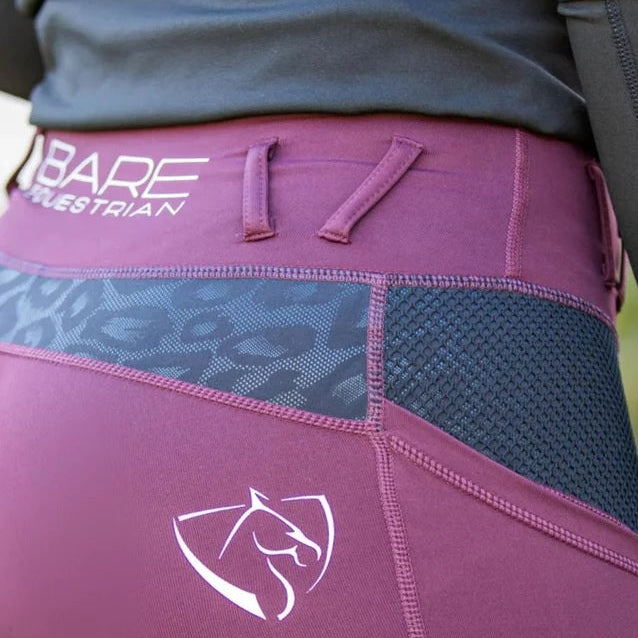 Close-up of maroon horse riding tights with a logo detail.