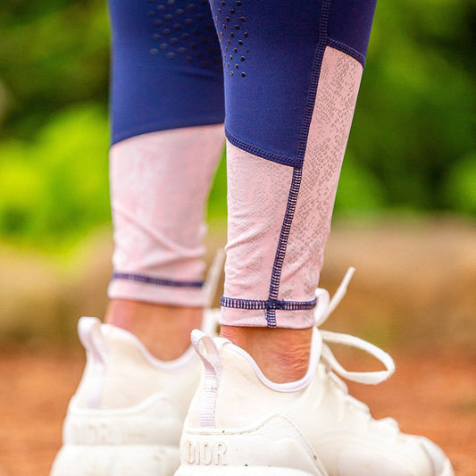 Close-up of patterned horse riding tights and white sneakers outdoors.