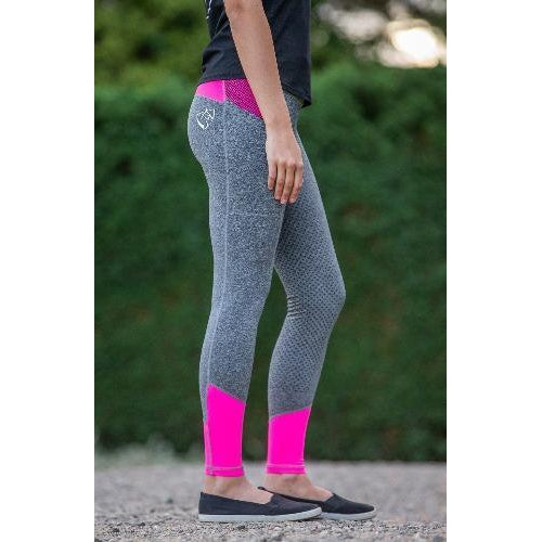 Person standing in gray and pink horse riding tights outdoors.