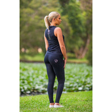 Woman in black horse riding tights standing in a green park.