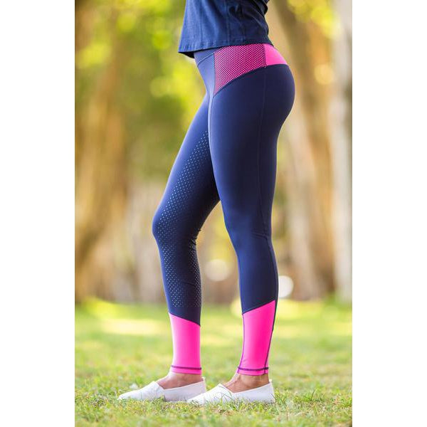Person in navy and pink horse riding tights standing outdoors.