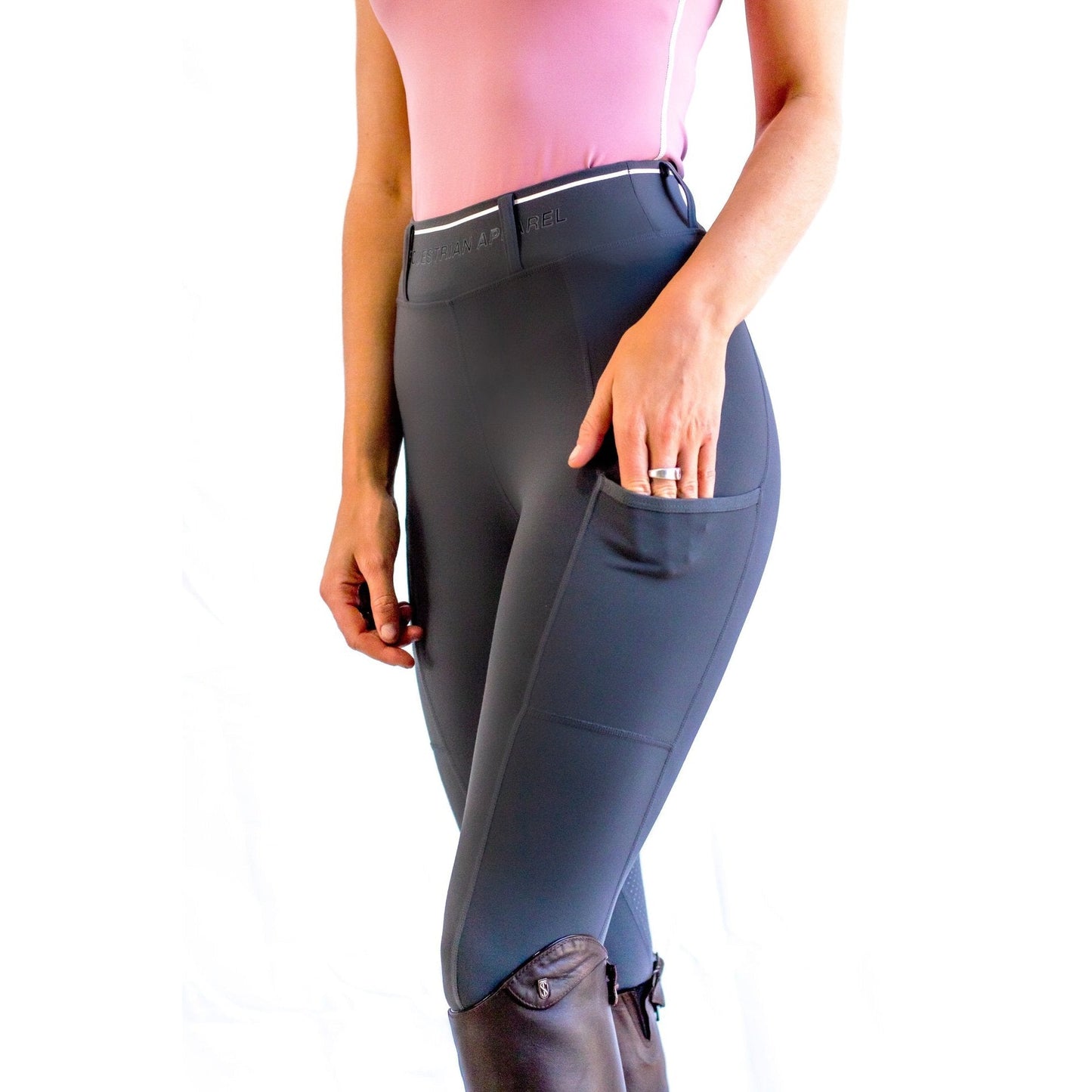 Woman in Horse Riding Tights standing against a white background.