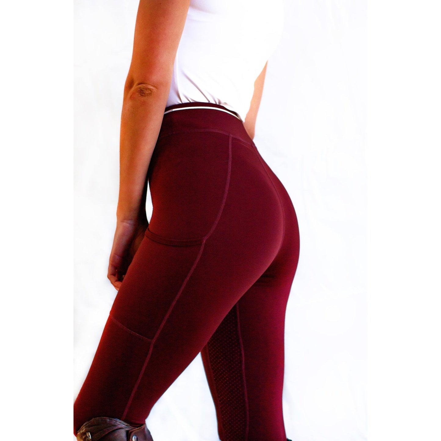 Person wearing maroon horse riding tights against a white background.