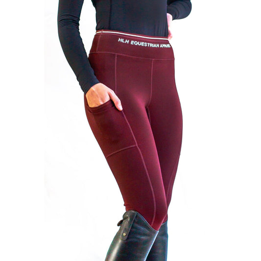 Person wearing burgundy horse riding tights with black boots.