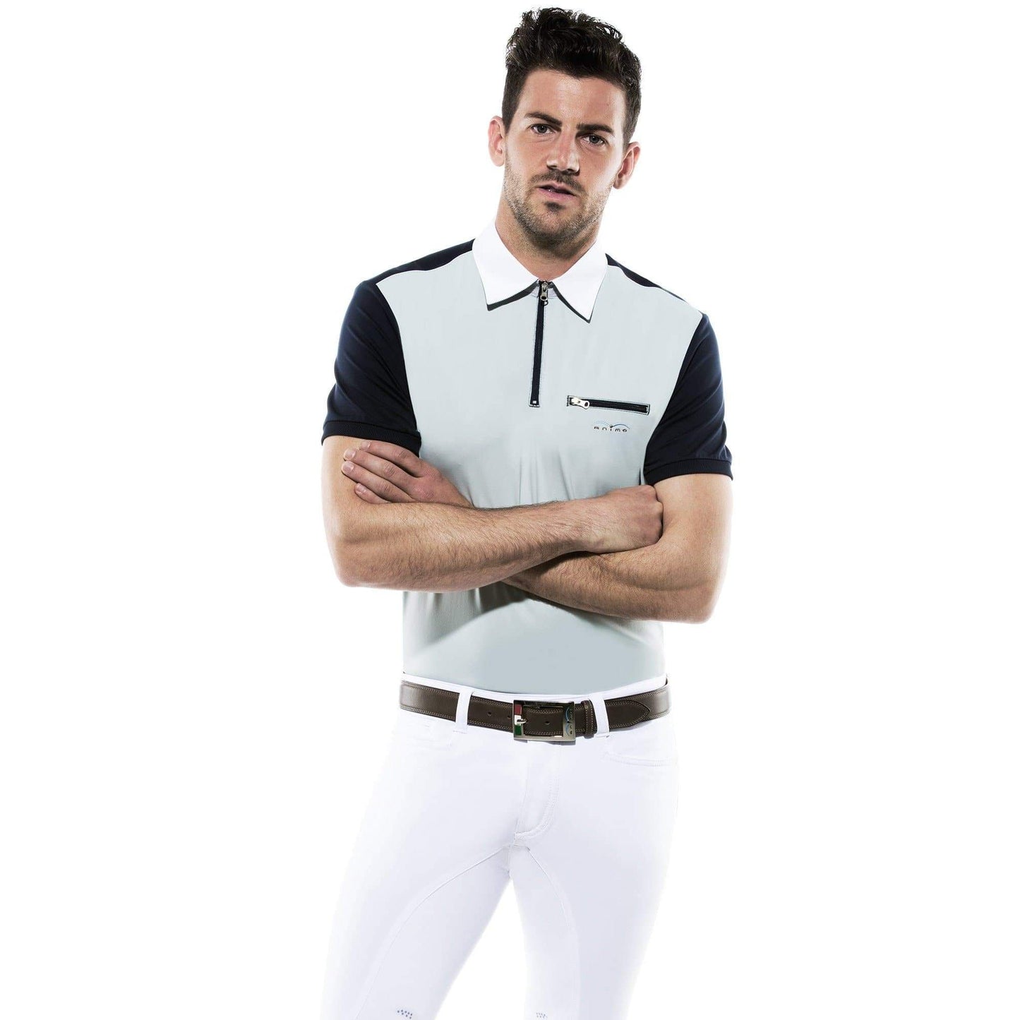 Man in Animo polo shirt, crossed arms, white breeches, confident posture.