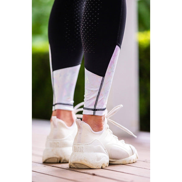 Person wearing horse riding tights and white sneakers on wooden floor.