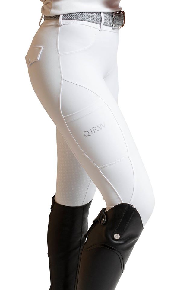 Person wearing white equestrian horse riding tights with tall black boots.