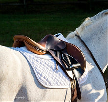 White horse with Thinline saddle and quilted saddle pad.