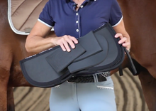Person holding a Thinline saddle pad in both hands.