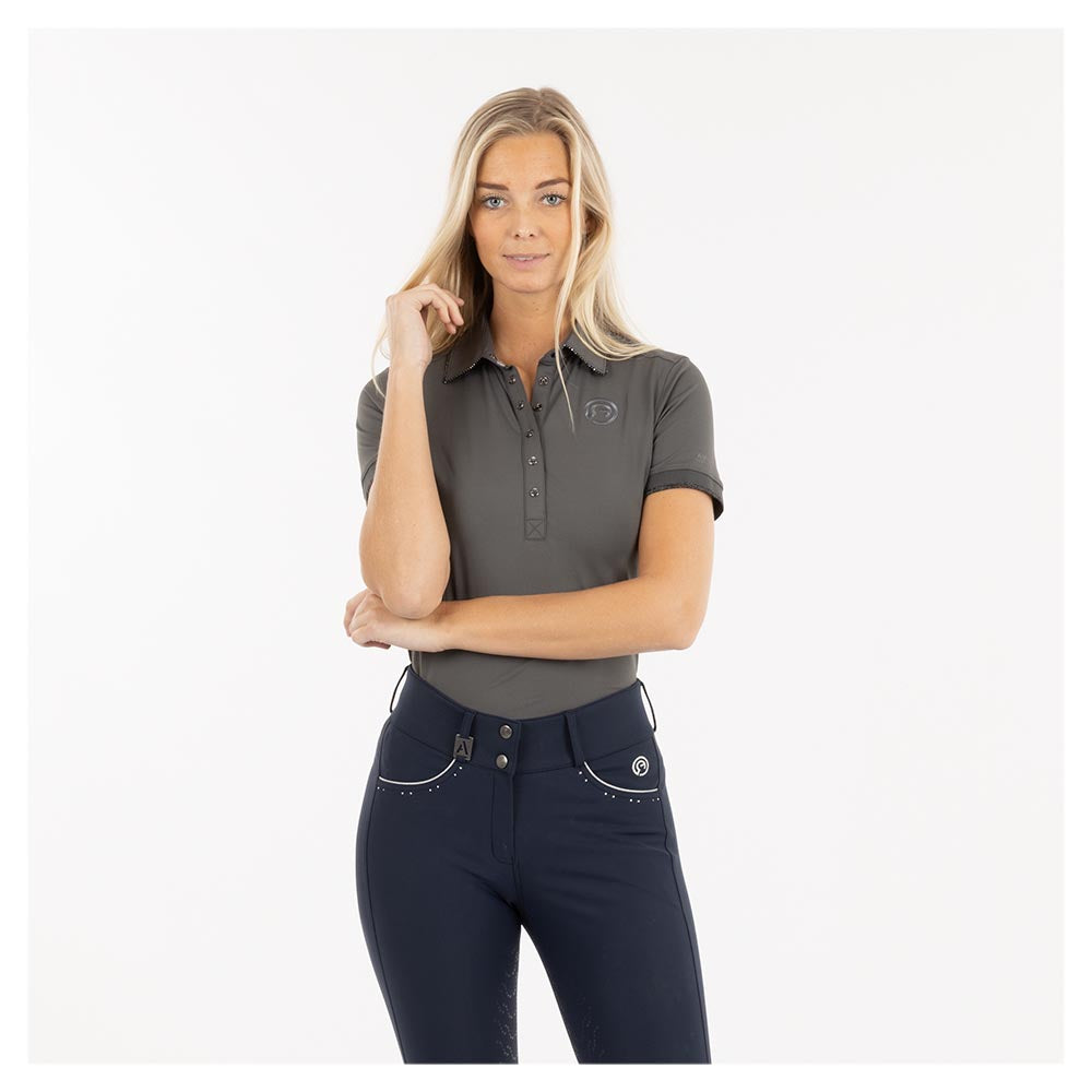 Woman in ANKY equestrian polo shirt and breeches, confident pose.