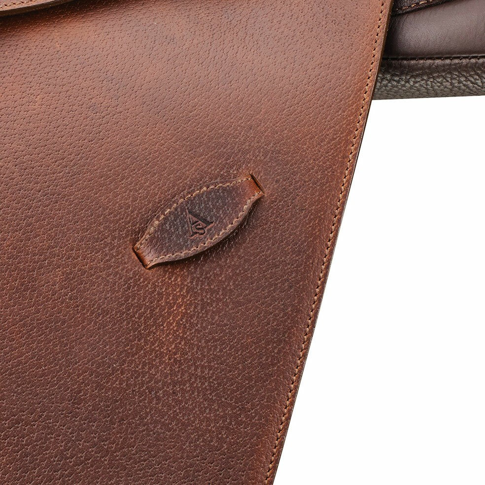 Close-up of Arena Saddles logo on textured brown saddle leather.