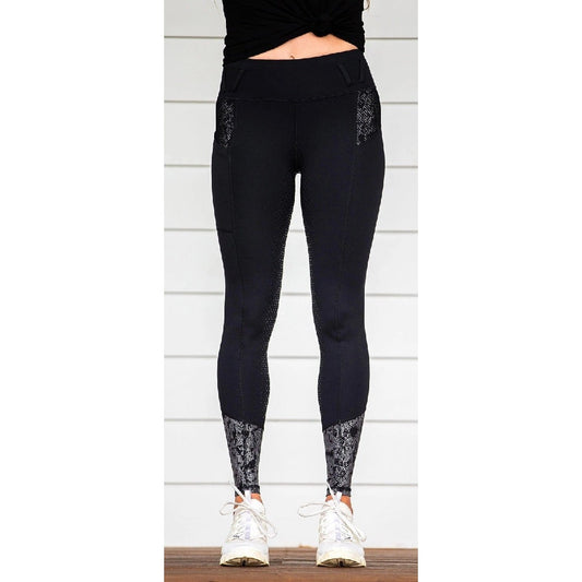 Person standing in black horse riding tights with lace details.