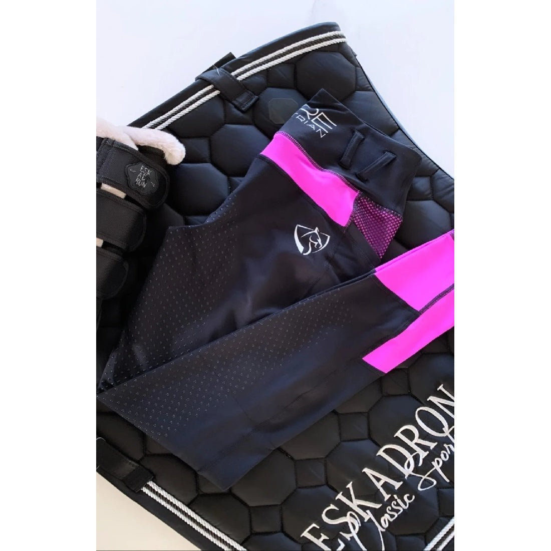 Black and pink horse riding tights with equestrian gear on side.