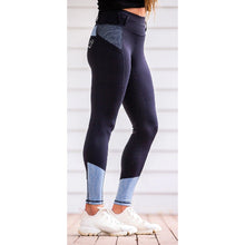 Person standing in profile wearing navy horse riding tights.