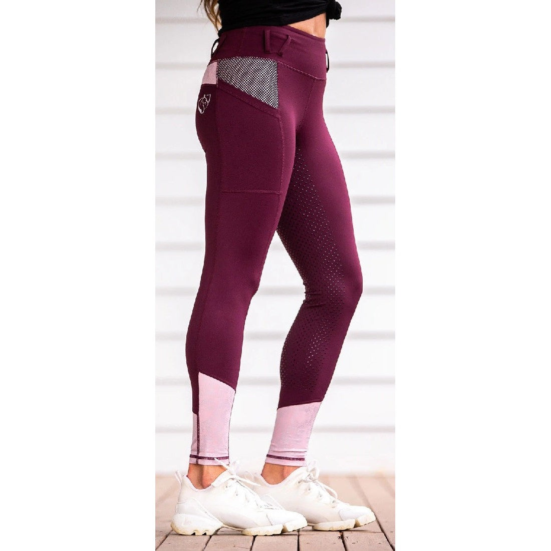 Woman wearing stylish burgundy horse riding tights with white sneakers.