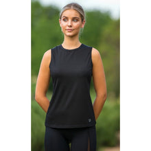 Woman in black tank top and horse riding tights standing outdoors.