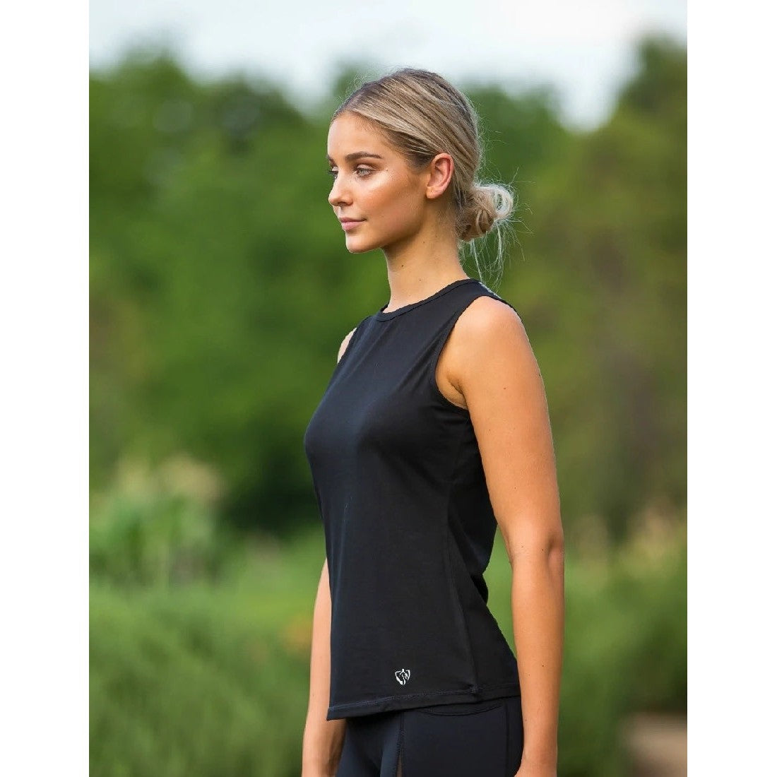 Woman in black sleeveless top, possibly wearing horse riding tights.