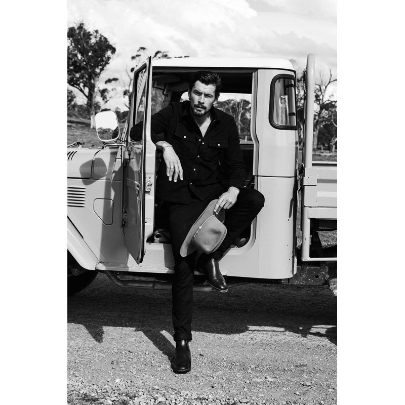 Man in black outfit with Baxter Boots by classic white truck.