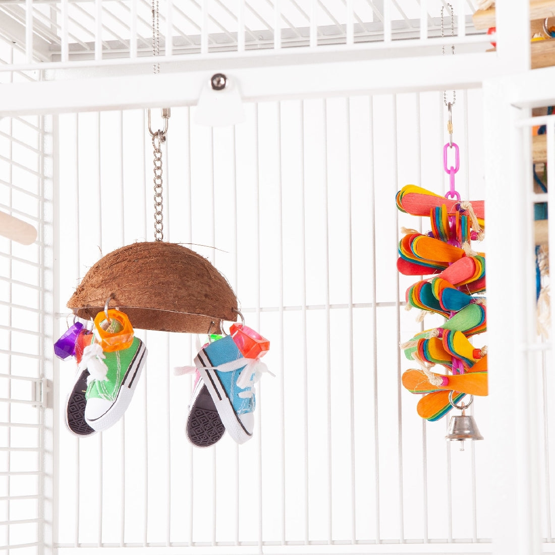 Colorful bird toys hanging inside a white cage, type: bird toy.