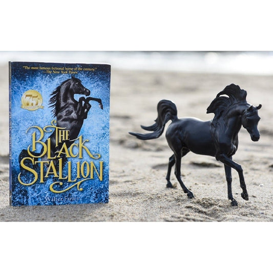 Breyer Horse Toy running by "The Black Stallion" book on sand.