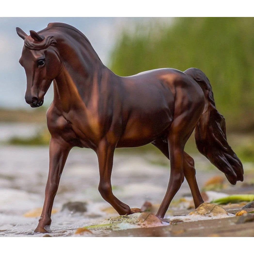 Breyer Horse Toy model posed elegantly on a rocky stream bank.