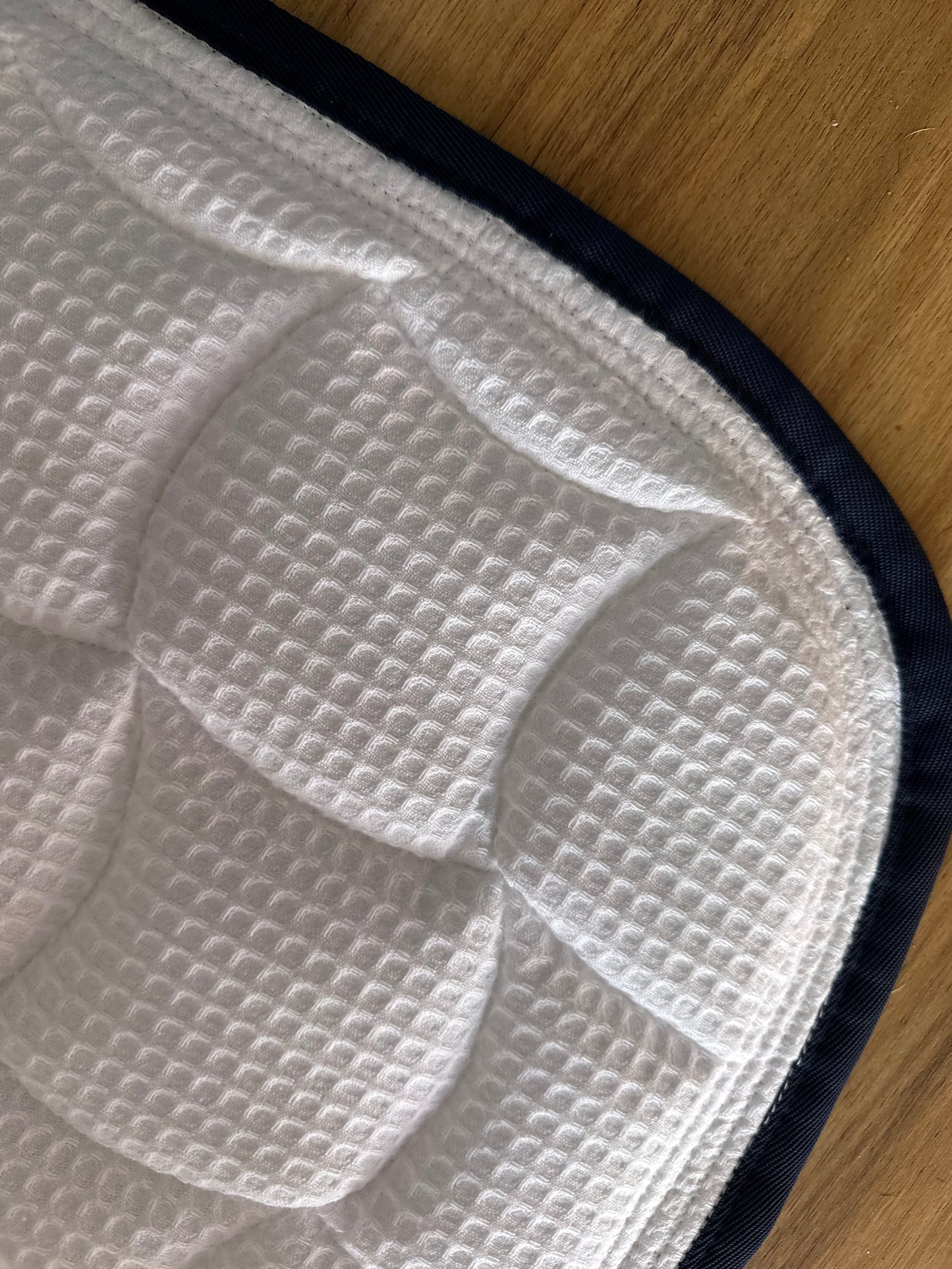 Alt text: Anna Scarpati white saddle pad with quilted design and navy trim.
