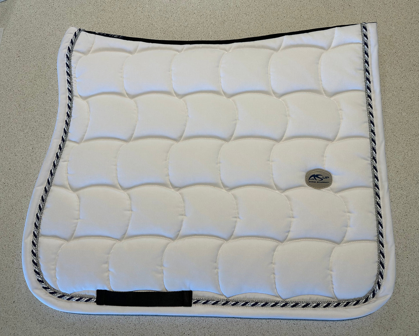 Anna Scarpati white quilted horse saddle pad with black trim.